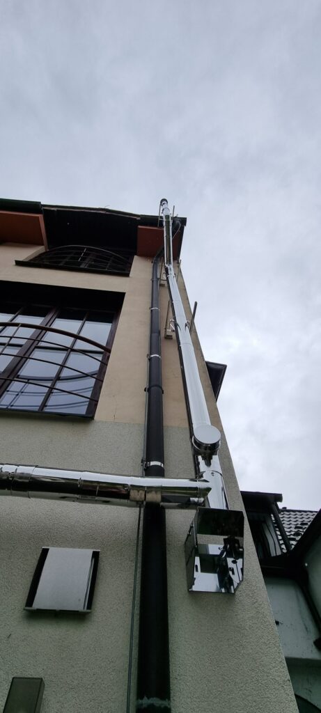 Nerezový fasádny komín v rodinnom dome vedený okolo balkóna a strešných okien